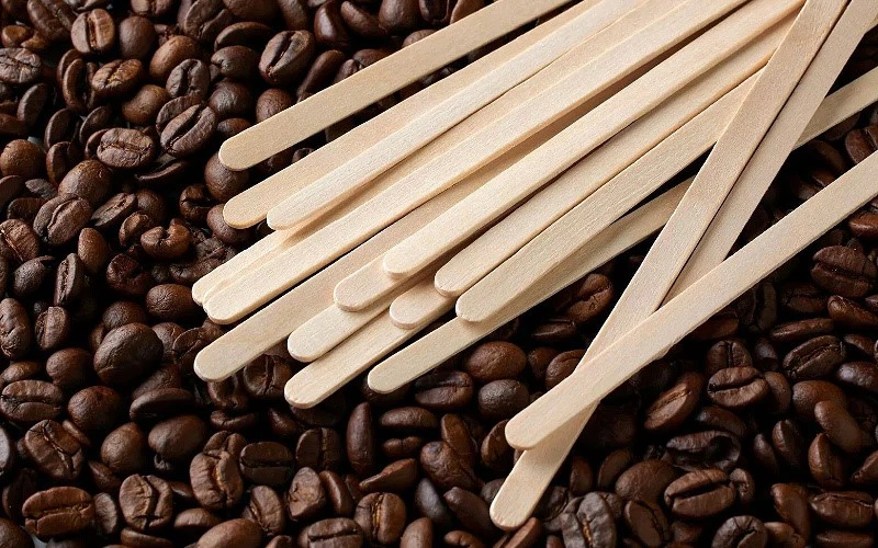 Custom branding wooden stir sticks displayed on roasted coffee beans Custom branding wooden stir sticks displayed on roasted coffee beans